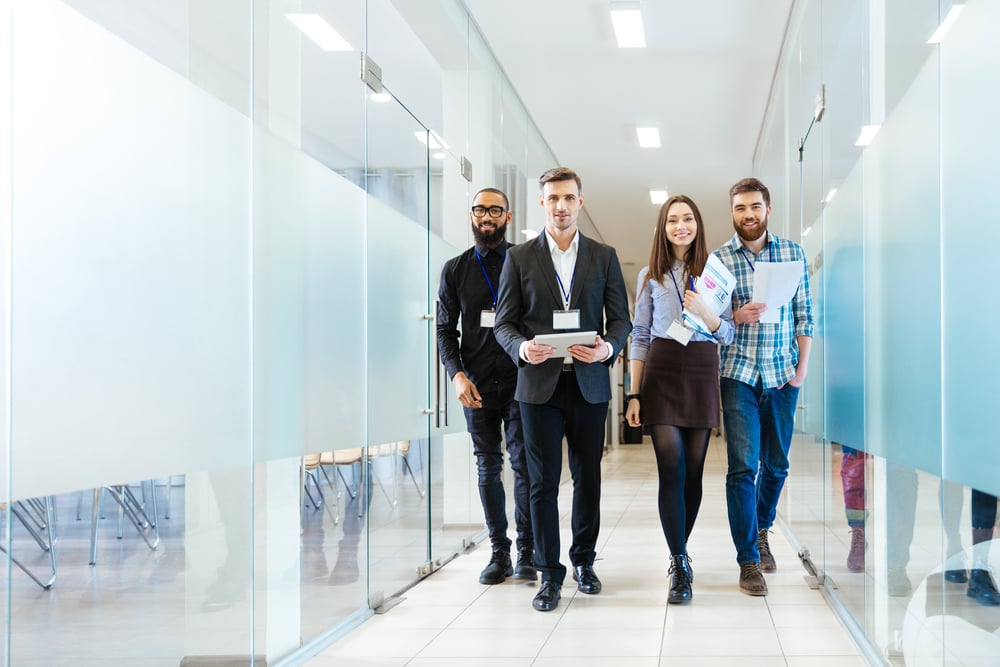 Full length of group of happy young business people walking the corridor in office together Full length of group of happy young business people walking the corridor in office together